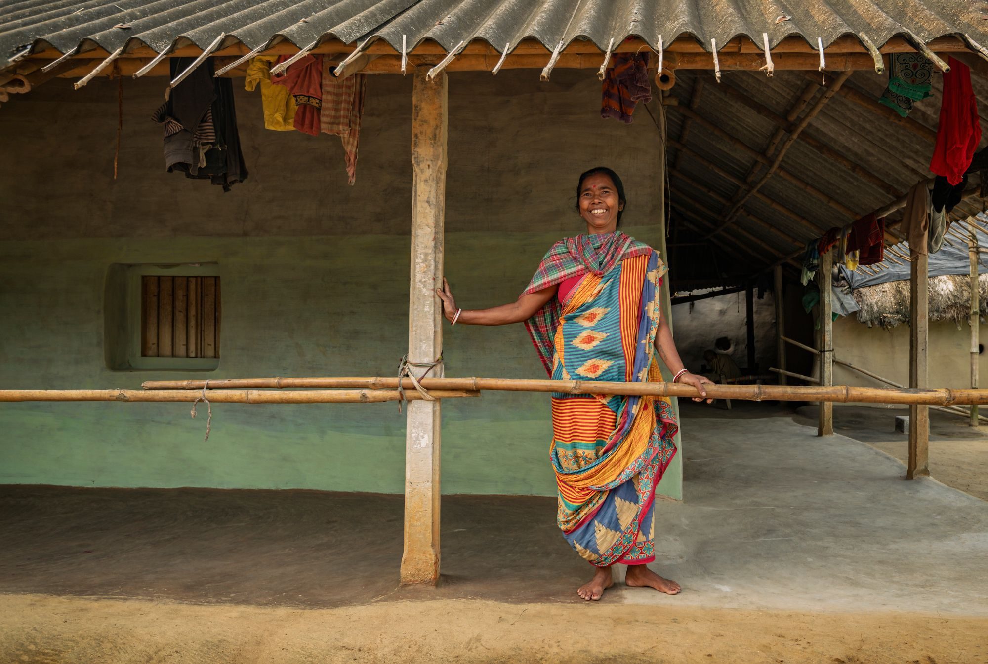 A woman in a rural Indian village standing at the doorway of her home, looking out